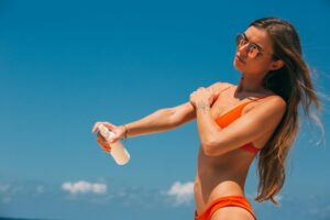 Moteris tepanti apsauginį kremą nuo saulės lauke saulėtą vasaros dieną